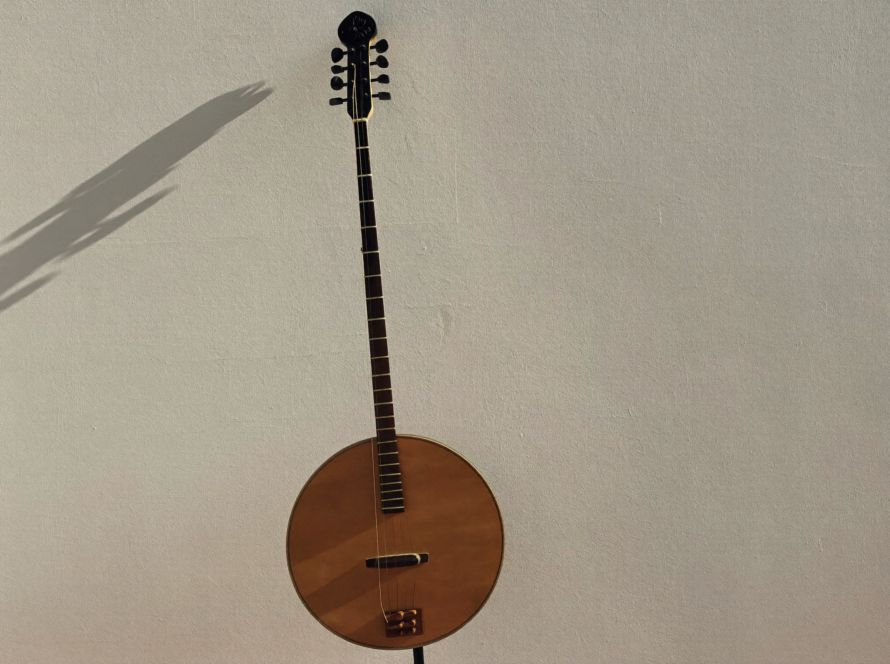 Bir kişinin elinde bağlama tutması, arka planda bulanık bir gitar